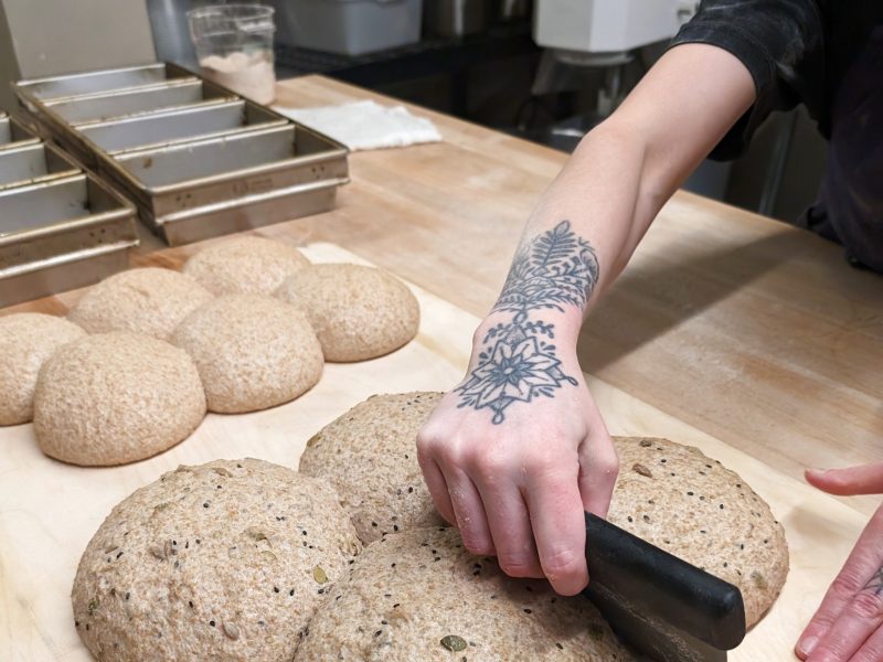 A baker shapes dough at Tommy's Whole Grain Bakery in Strathcona